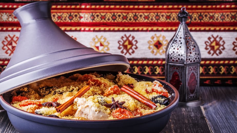Tajine mit Couscous, Zimtstangen und orientalischer Laterne