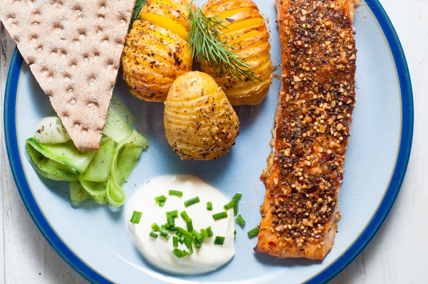 Lachs mit Senfkruste, Fächerkartoffeln und Gurkensalat auf blauem Teller