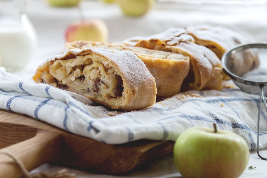Angeschnittener Apfelstrudel mit Puderzucker auf einem Küchentuch