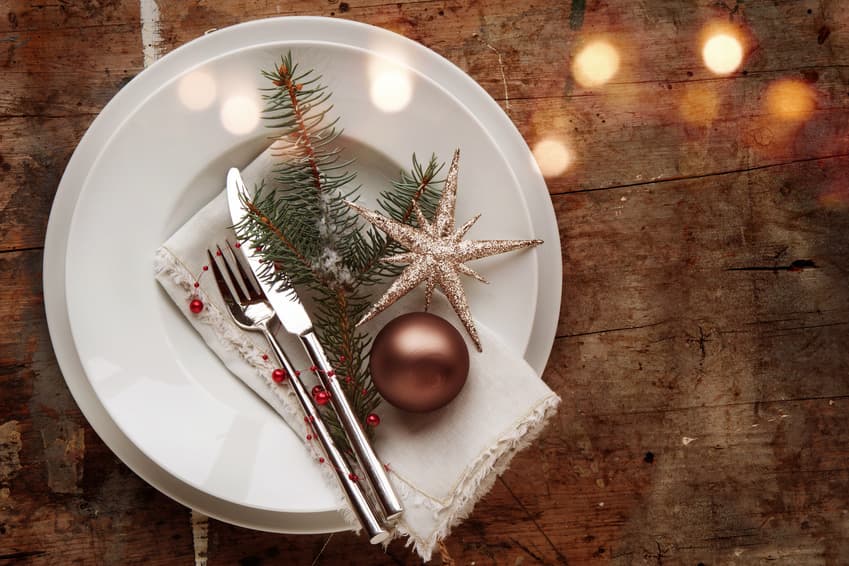 Weihnachtlich gedeckter Teller mit Tannenzweig, Stern und Besteck auf Holz