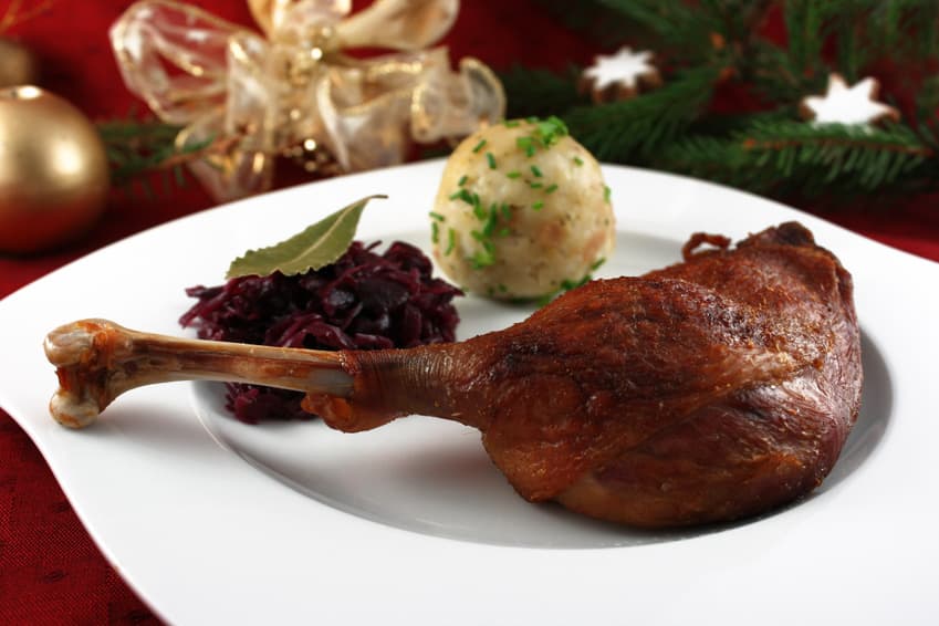 Gänsekeule mit Rotkohl und Knödel vor Weihnachtsschmuck