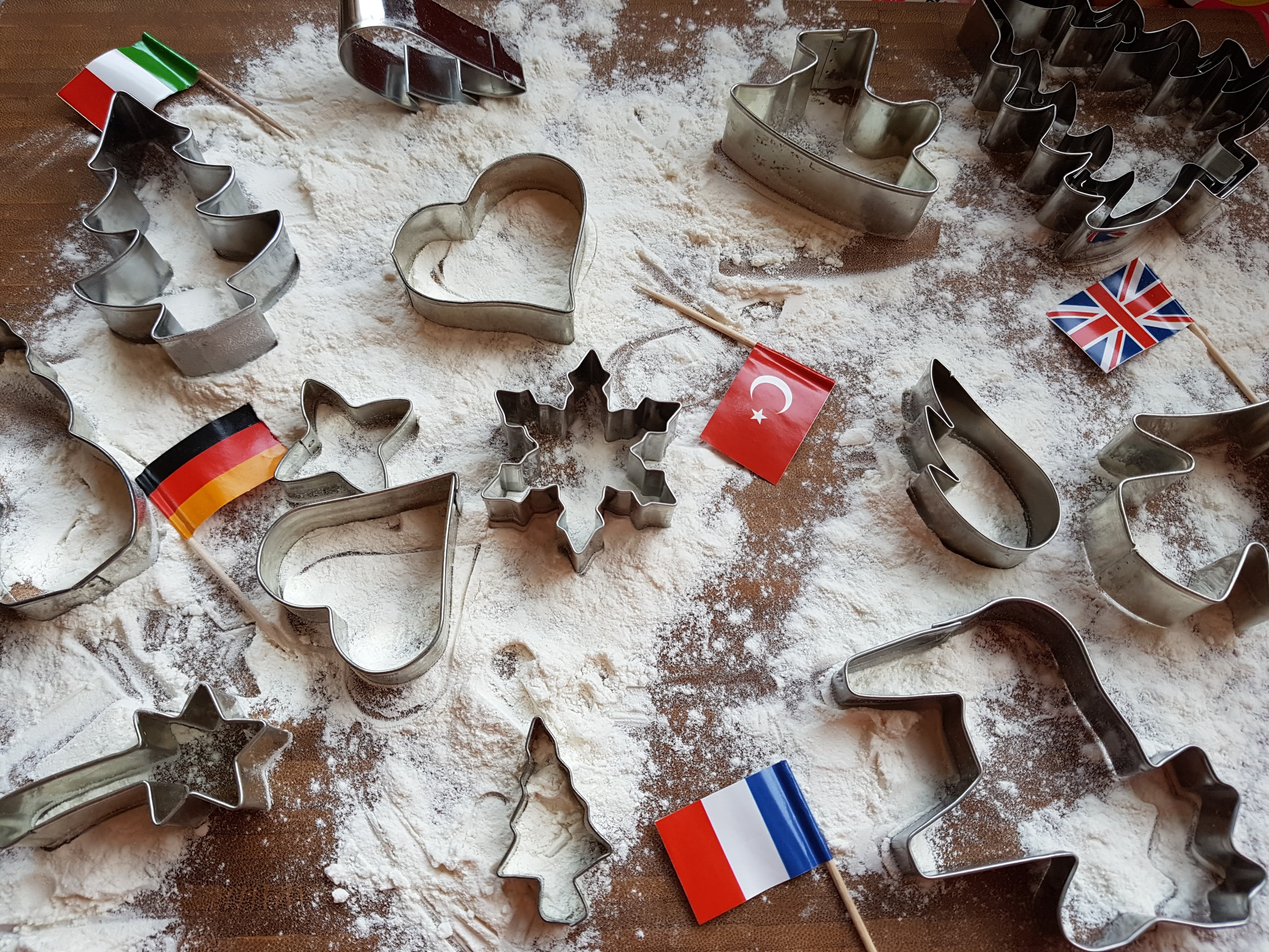 Ausstechformen und kleine Länderflaggen auf mit Mehl bestäubtem Holz