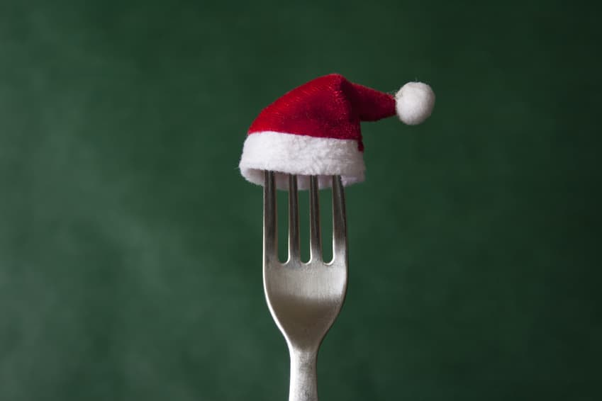 Gabel mit kleiner Weihnachtsmütze vor grünem Hintergrund