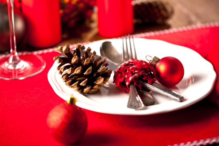 Weihnachtlich gedeckter Teller mit Tannenzapfen, Kugeln und Besteck