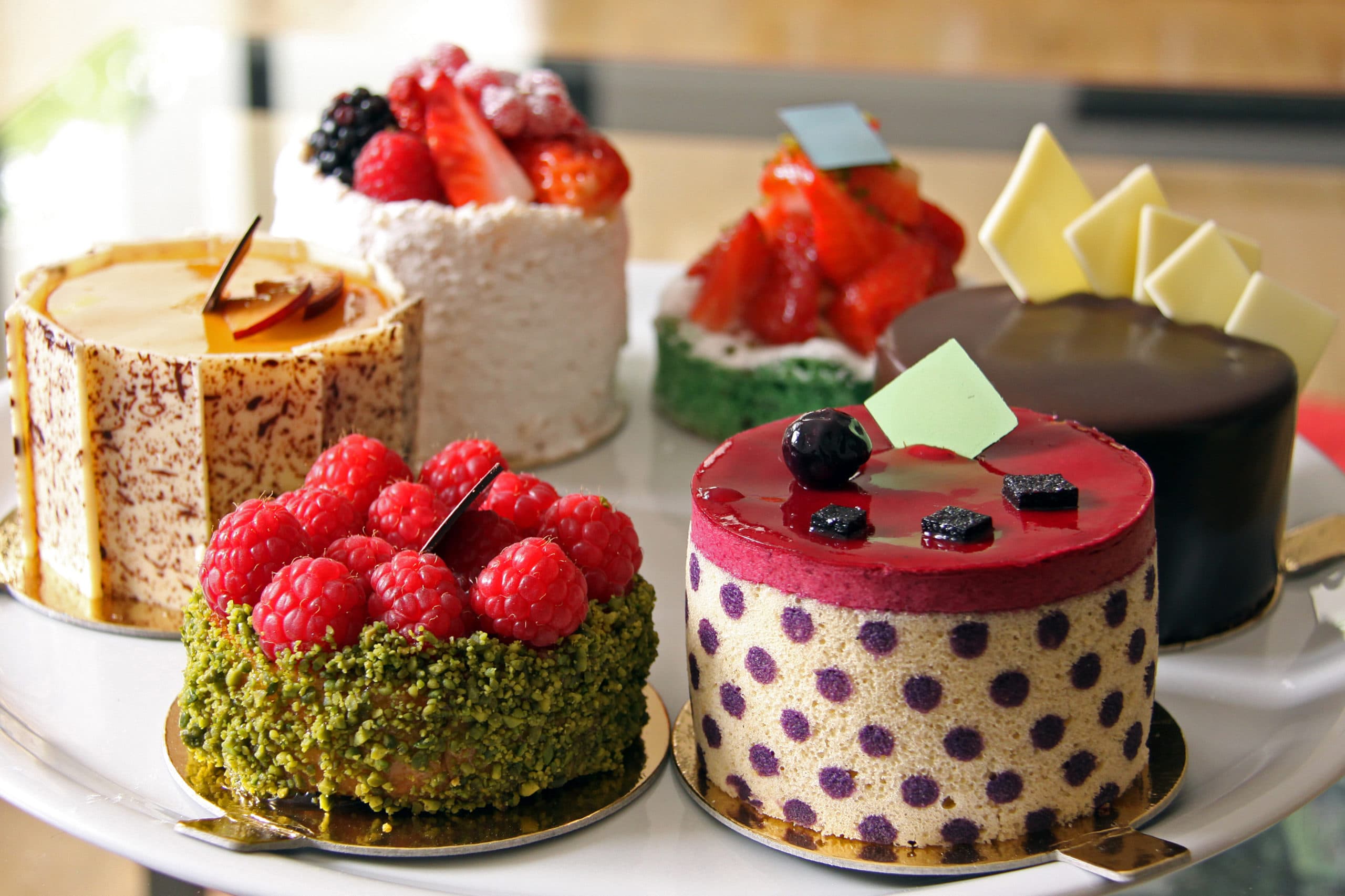Mehrere kleine Törtchen mit Beeren, Pistazien und Schokolade
