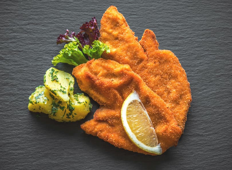 Wiener Schnitzel mit Zitronenspalte und Petersilienkartoffeln auf Schiefer