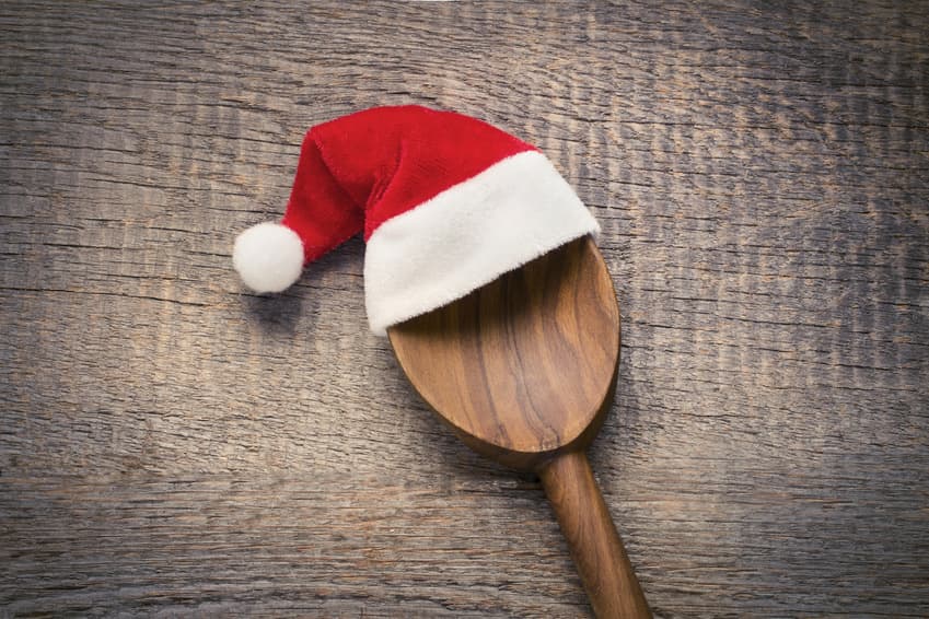 Holzlöffel mit kleiner Weihnachtsmütze auf rustikalem Holz