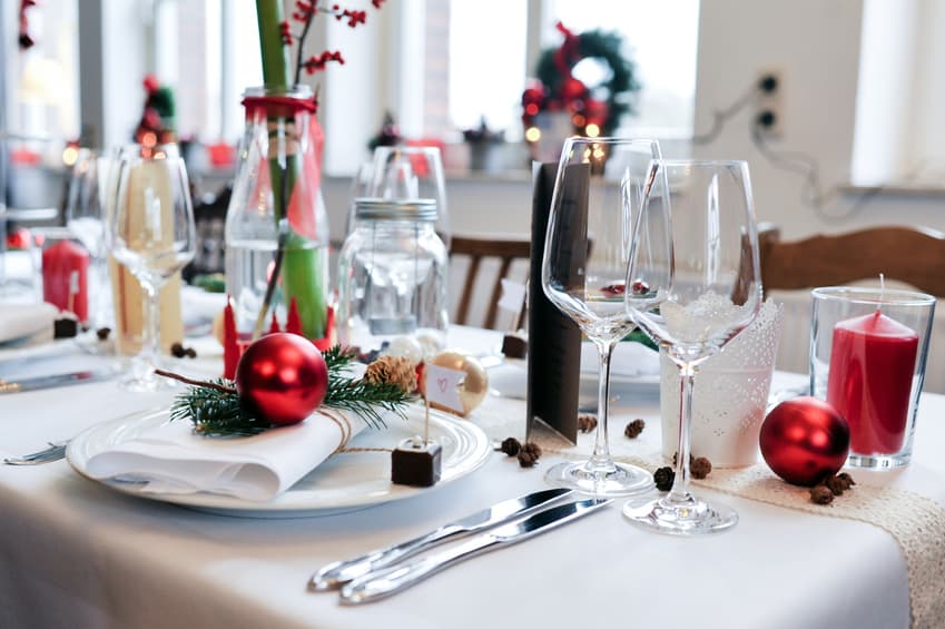 Festlich gedeckter Tisch mit Weingläsern, roten Kugeln und Kerze